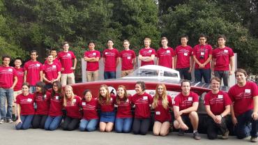 Stanford solar car project student team surround their latest solar car in this photo taken outside of the Automotive Innovation Facility.