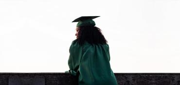 Graphic of the back view of a woman wearing a cap and gown