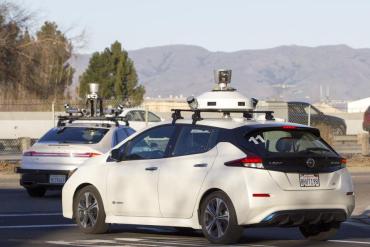 Photo of two autonomous vehicles with lidars on top of vehicle.