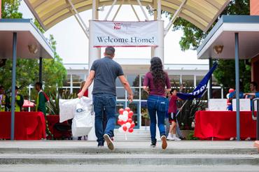Photo of father and daughter at entrance to dorm with sign, 'Welcome Home!'