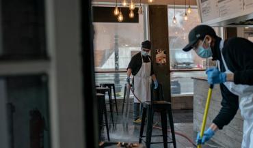 Photo of workers at a restaurant cleaing while wearing masks