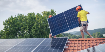 Photo of workers installing solar panels on a roof