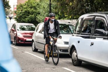 Photo of bicyclist adjacent to vehicles commuting