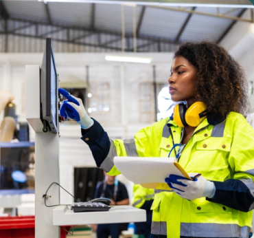 Photo of person in a warehouse, entering data into a workstation on a manufacturing line