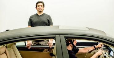 Pablo Paredes, standing outside of driving simulator vehicle, and graduate student Peter Washington driving in the simulator vehicle, test strest-mitigation technology in Stanford's Volkswagen Automotive Innovation Lab.