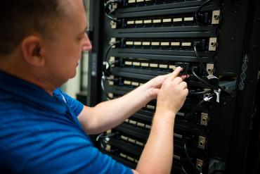 Photo of a person working on connecting wires on a server rack