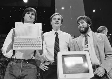 Photo of Steve Jobs, John Sculley (the C.E.O. of Apple) and Steve Wozniak unveil the new Apple IIc computer in 1984.