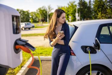 Photo of woman charging her EV at a charging station.