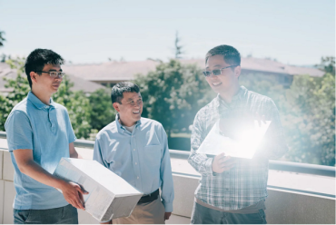 Postdoctoral scholar Ming Zhou (right) holds up a panel that cools down even when placed in direct sunlight. 