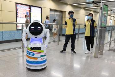 Photo of humanoid robot next to two people in a lobby.