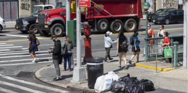 Photo of an intersection corner with pedestrian and vehicles.