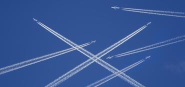 Image of blue sky with jets flying in different directions with contrails